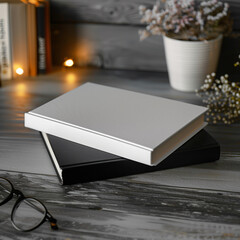 Mockup of a new book with blank white and black cover in modern neat style on a wooden desk in a room at night background. Square template for social media post for books and advertisement.