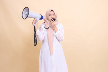 girl asian young wearing a hijab at the camera shouts angrily holding a loudspeaker megaphone and...