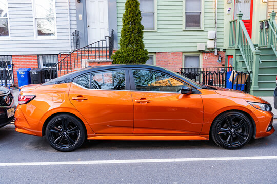 New York City, USA - March 26, 2024: 2022 Nissan Sentra orange modern car parked outdoor, side view
