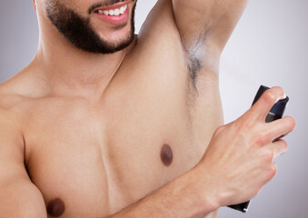 Fototapeta premium Studio, grooming and man with deodorant, smile and body care with confidence, protection and skin. Skincare, health and happy male model with spray, armpit and product isolated on grey background