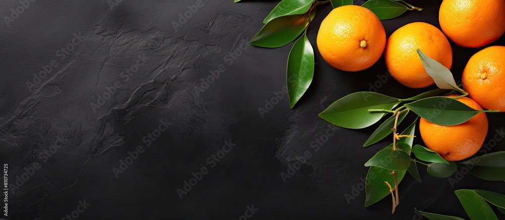 Poster top view of a flat lay fruit composition featuring an orange or tangerine with leaves placed on a bl