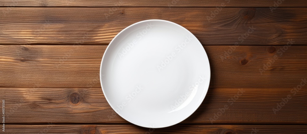 Poster Top view of a white ceramic plate placed on a wooden background and there is ample copy space in the image