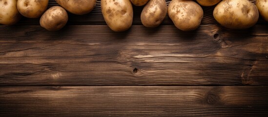 A wooden background showcases a close up view of whole potatoes leaving room for additional images or text - Powered by Adobe