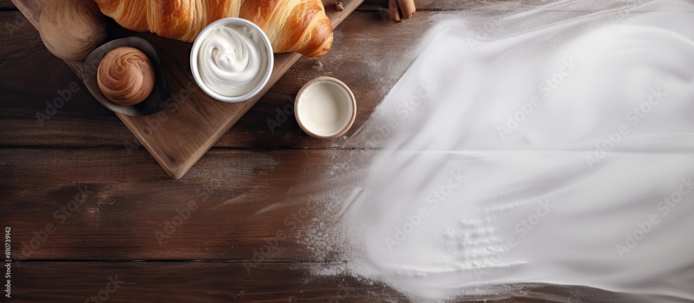 Poster on a wooden table there is a top view of a fresh croissant placed on white fabric additionally there