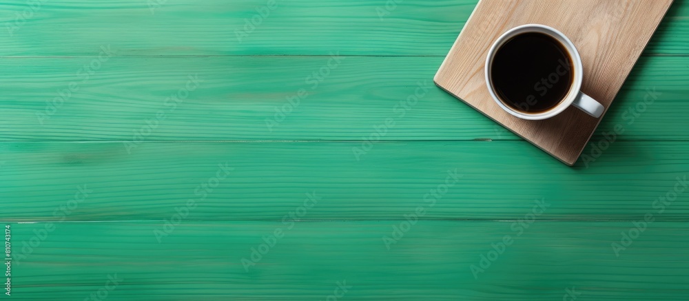 Poster a top view of a wooden desk with a green screen smartphone and a paper coffee cup providing ample co