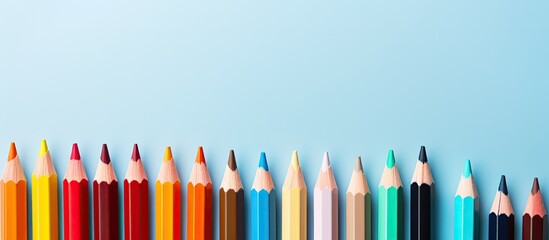 Colorful pencils arranged on a light blue background providing ample copy space for your text The image is captured from an aerial perspective conveying the educational concept