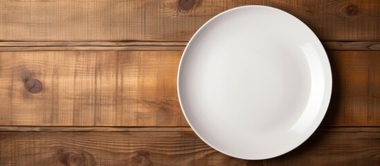 Top view of a white ceramic plate placed on a wooden background and there is ample copy space in the image