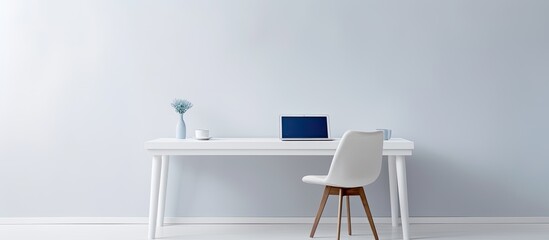 A white table with a chair and a laptop creating a minimalist setting with copy space image