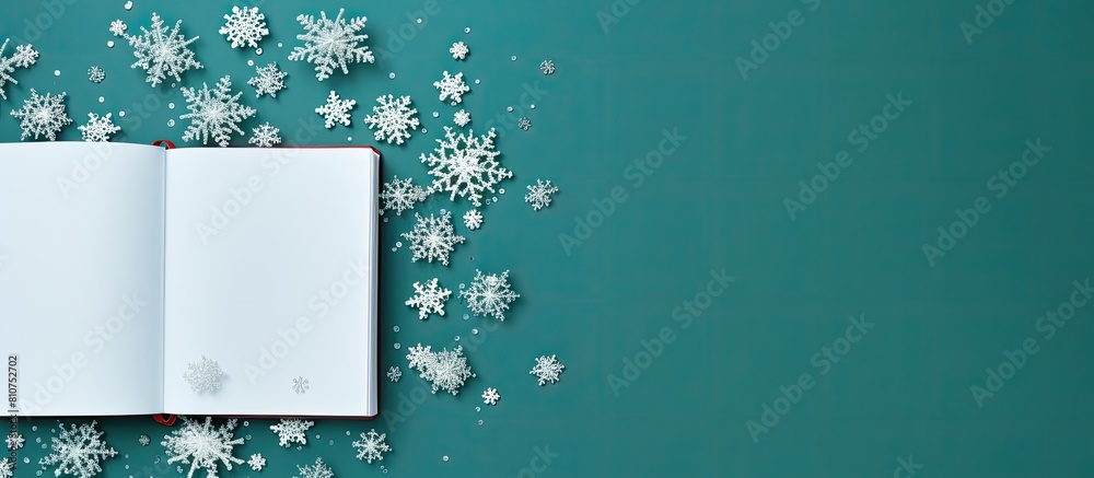 Fototapete The image depicts an open notebook alongside delicate snowflakes set against a vibrant green background This top down view offers ample space for personalization or additional elements