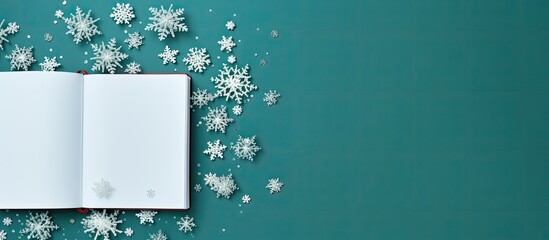 The image depicts an open notebook alongside delicate snowflakes set against a vibrant green background This top down view offers ample space for personalization or additional elements