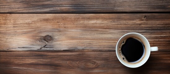 A top down perspective showing an old wooden surface with a cup of black coffee perfect for a copy space image 108 characters - Powered by Adobe
