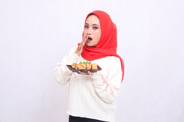 indonesia woman wearing a hijab is shocked to cover her mouth and bring up a plate containing sushi (Japanese food). Beautiful Muslim women are used for culinary, food and advertising content