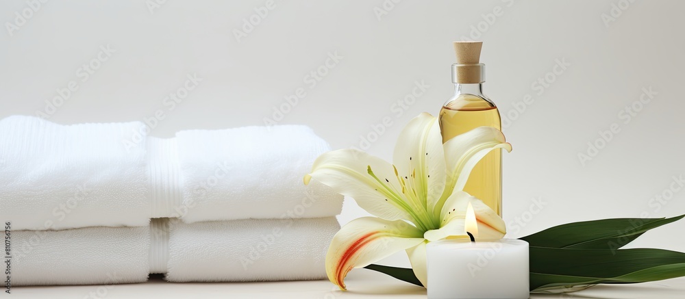 Poster a serene wellness setting showcases a beautiful lily a towel a candle and an oil bottle on a white b