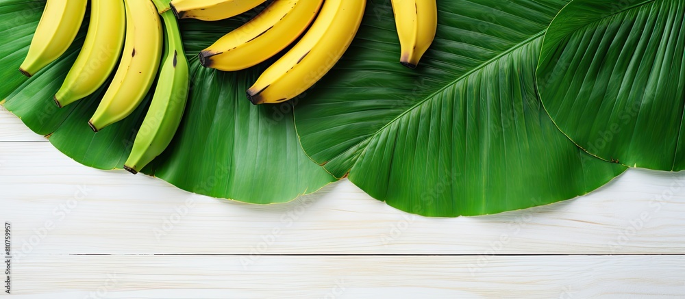 Poster a tropical fruit the banana is placed on a white wooden table alongside vibrant green leaves the top