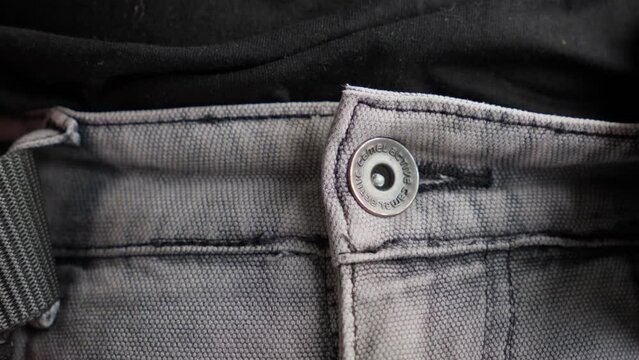 Close-up of a man unbuckling a tactical black belt from his trousers