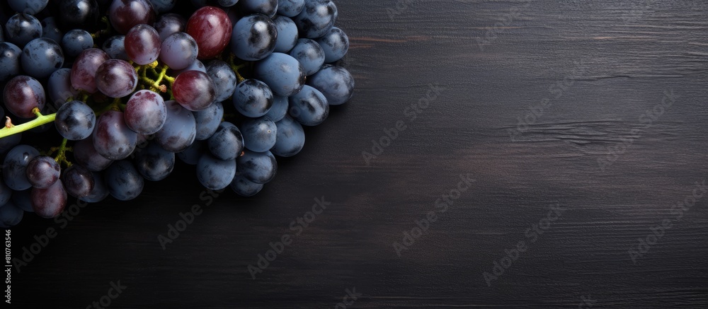 Poster the top view shows a collection of plump ripe blue grapes resting on a dark scratched surface in thi