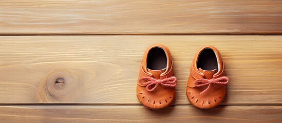 Top view of adorable baby shoes placed on a wooden background creating a charming composition with copy space for an image