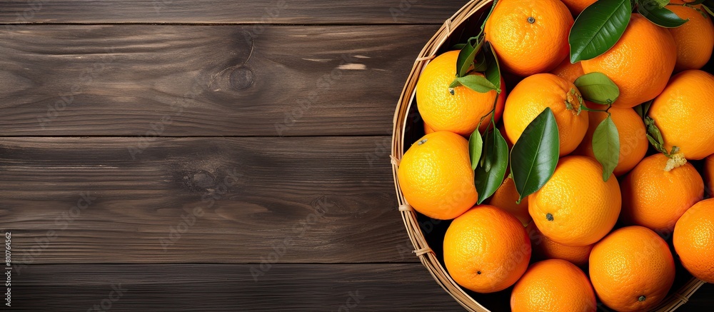 Poster The copy space image shows a top view of a basket filled with freshly picked oranges resting on a wooden table