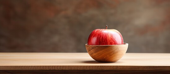A close up photo of a fresh apple resting in a wooden bowl on a table with ample blank space around the image - Powered by Adobe