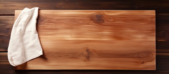 Wooden cutting board with a kitchen cloth placed on a wood background creating an empty space for an image. Creative banner. Copyspace image