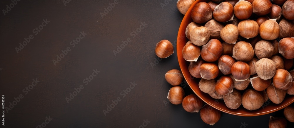 Aufkleber Top view of a bowl filled with hazelnuts on a grey background providing copy space for the image