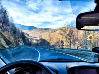 Car salon, windshield, hand of woman on steering wheel and landscape. View from seat of driver on...
