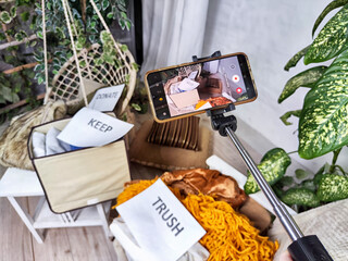 The blogger takes off stacks of clothes and signs with the words save, donate, throw away on cell...