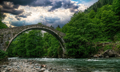 Ancient stone arch bridge and mountain river