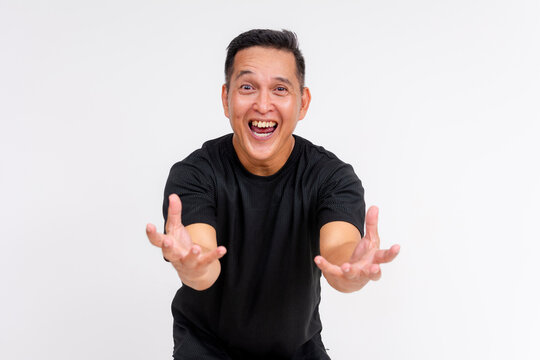 An enthusiastic middle-aged Asian man with outstretched arms, appearing to catch or grope something invisible, isolated on a white background.