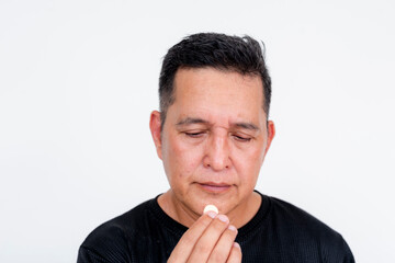 Middle-aged Asian man hesitant to take medication, isolated on white