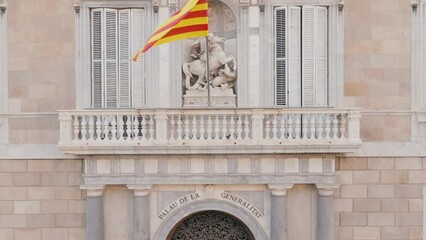 Aerial close up of Catalan flag on Palau de la Generalitat in Barcelona, Catalonia, Spain. Historic palace entrance and Sant Jordi statue. Old Gothic facade of government building.