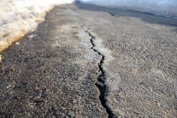 Close-up of cracks in the asphalt pavement, sidewalk in perspective, damage to the road surface in...