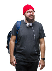 Young hipster man wearing red wool cap and backpack over isolated background looking away to side with smile on face, natural expression. Laughing confident.