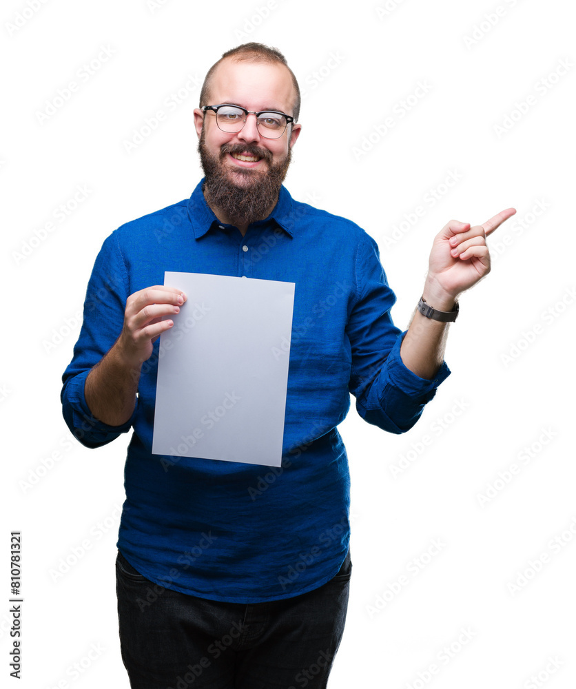 Sticker young hipster man wearing glasses and holding blank paper over isolated background very happy pointi