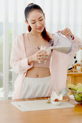 Sporty girl in fitness sport wear drinking healthy smoothie beverage that made for mix fruit and...