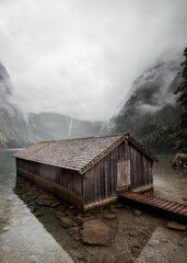 Wooden boathouse on the lakeshore, covered in fog