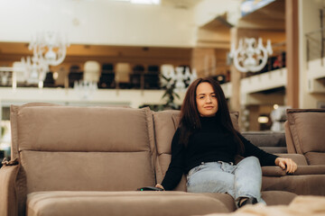 Joyful woman in furniture center chooses best sofa for her apartment