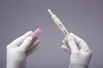 Positive pregnancy test in hands with white gloves