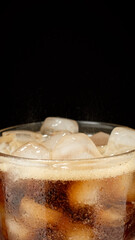 Refreshing drink in glass with ice, black background