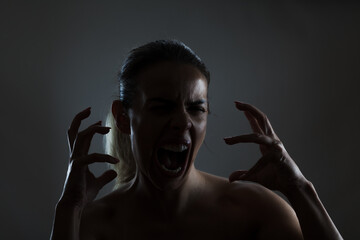 Expressive woman screaming powerfully, showing raw emotion and intensity in a dramatic lighting setup