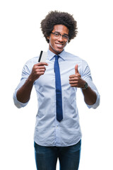 Afro american man holding credit card over isolated background happy with big smile doing ok sign, thumb up with fingers, excellent sign