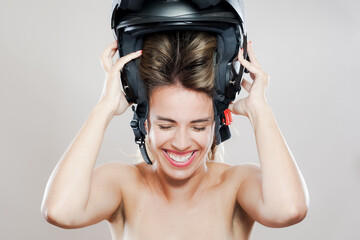 Young woman laughs while trying on a black motorcycle helmet, capturing a sense of joy and safety