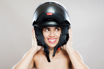 Happy young woman wearing a motorcycle helmet with a playful smile
