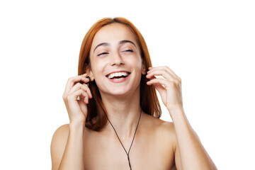 A joyful young woman enjoys listening to music with earphones, displaying a radiant smile and...