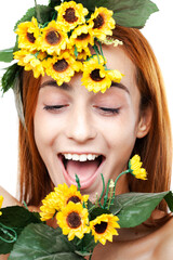 Vibrant close-up portrait of a cheerful young woman adorned with a sunflower crown, playfully sticking out her tongue.