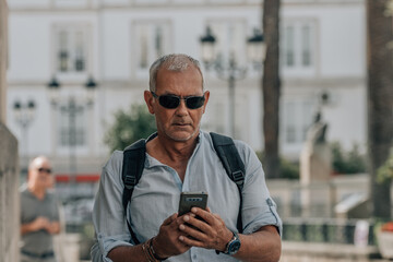 mature man with backpack and phone on the street