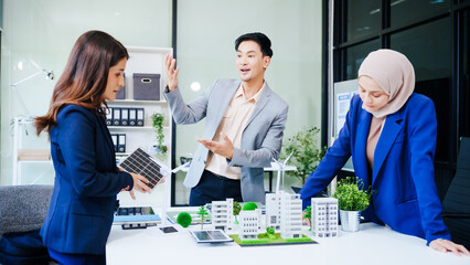 Trio of businesspeople, including a middle-aged Asian man and woman, strategize at their desk,...