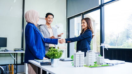 Three businesspeople convene at a desk with handshakes. middle-aged Asian man and woman discuss...