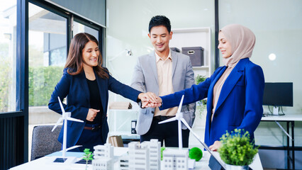 Three businesspeople gather at a desk, symbolizing unity with joined hands. Led by a middle-aged...