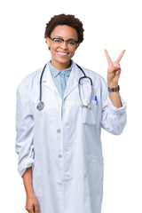 Fototapeta premium Young african american doctor woman wearing medical coat over isolated background smiling with happy face winking at the camera doing victory sign. Number two.
